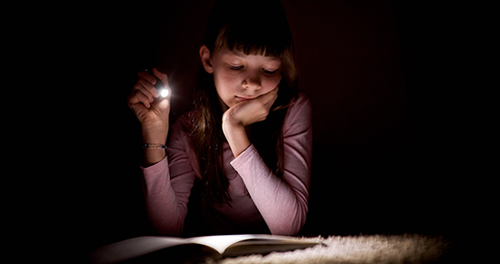 girl reading in the dark with a flastlight