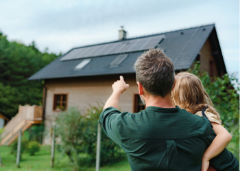 father and daughter looking at solar panels on house roof